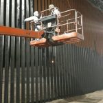 Two U.S. soldier apply paint to border wall. Dept. of Defense Photo.