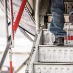 View of feet of illegal alien in shackles walking up steps to a plane.