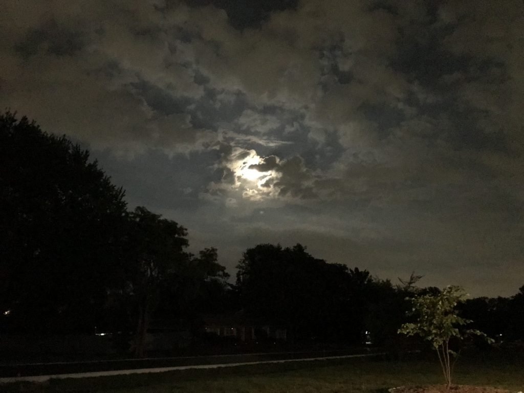 Moon behind dark clouds at night.