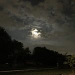 Moon behind dark clouds at night.