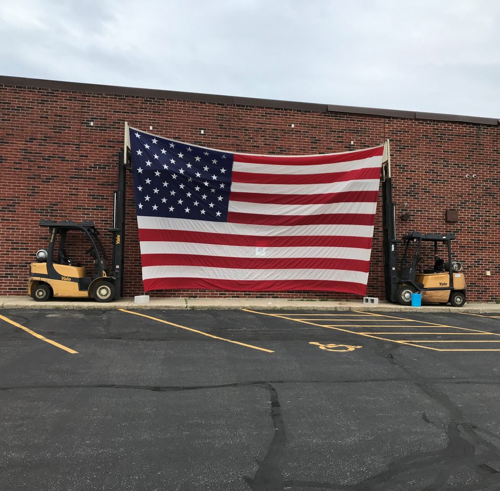 Two forklifts holding up an American flag.