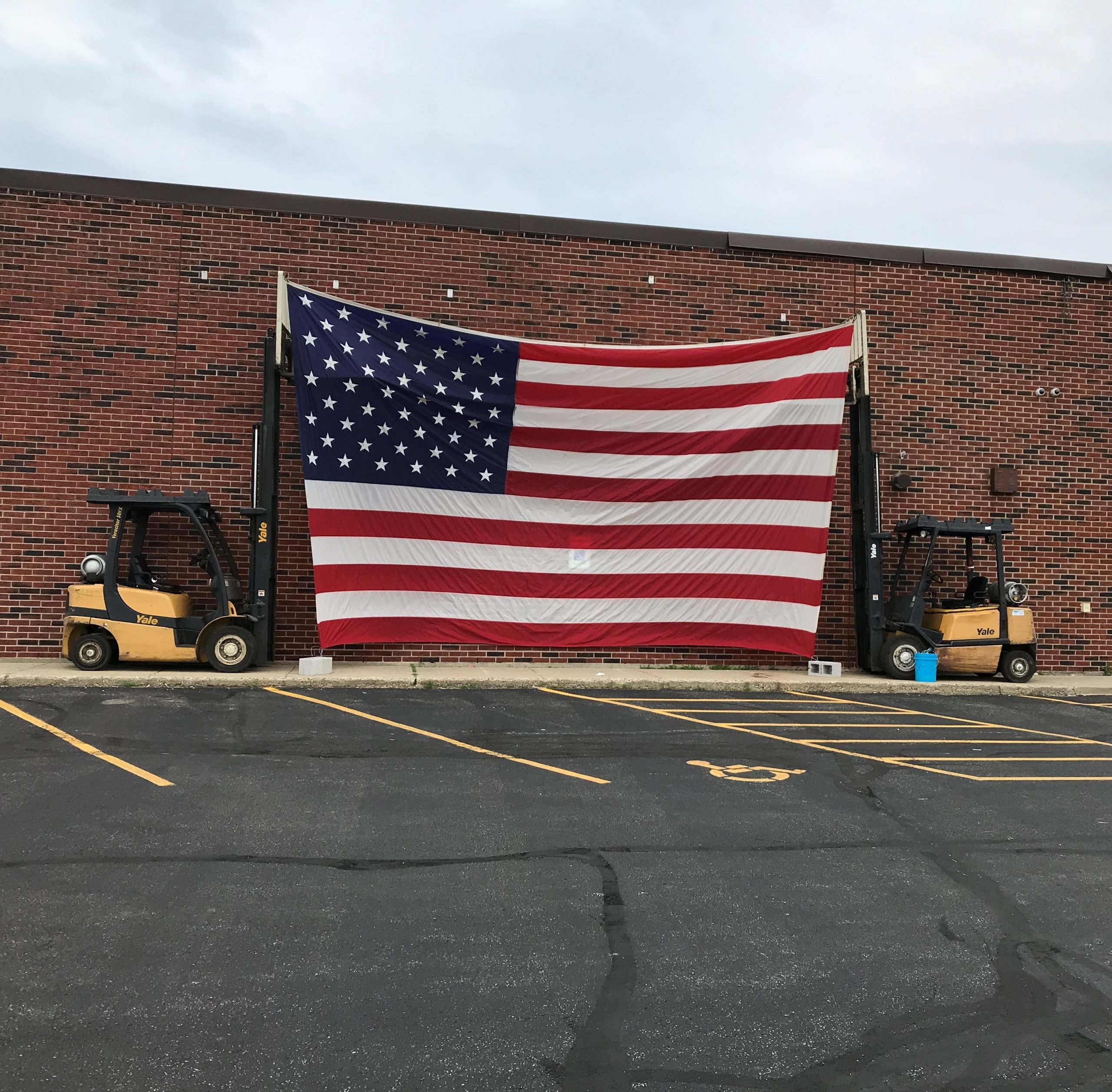 Two forklifts holding up American flag