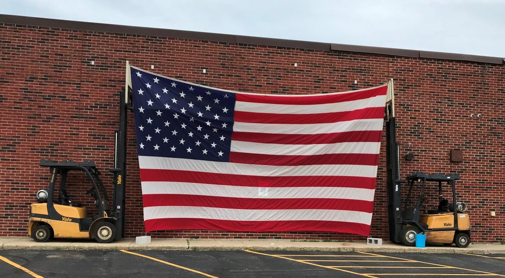 Two forklifts holding up American flag