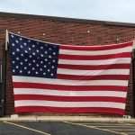 Two forklifts holding an American flag on the Fourth of July 2022.