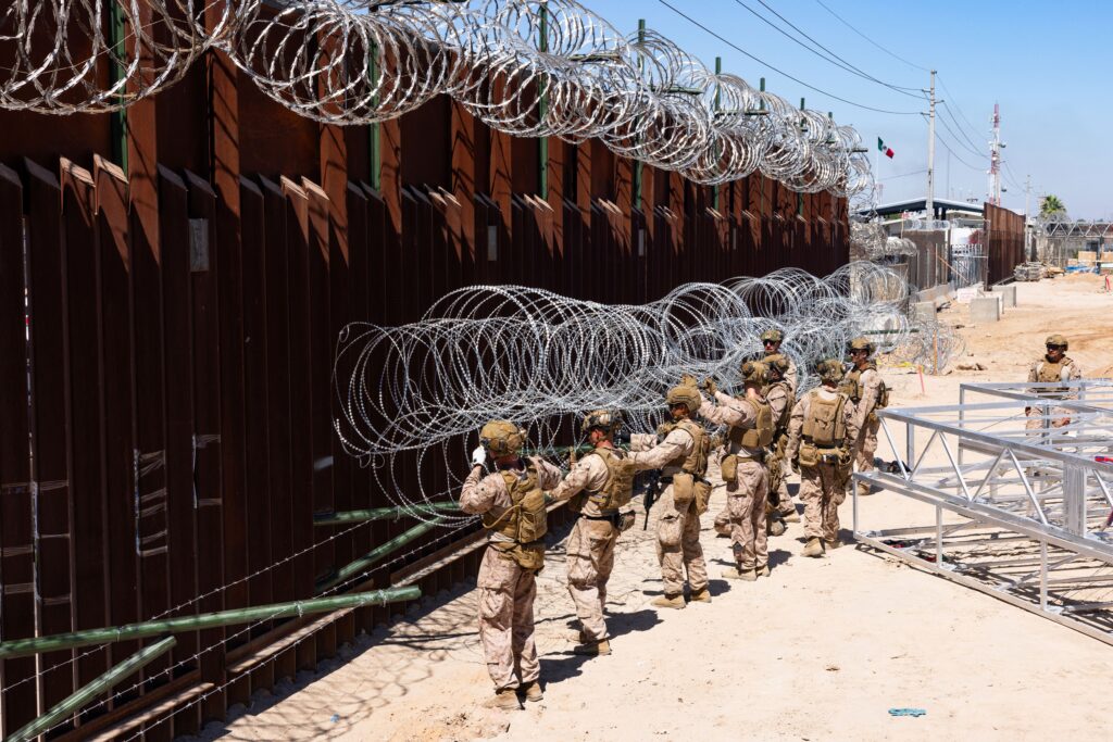 Marines assigned to Joint Task Force Southern Border place concertina wire on prefabricated brackets to reinforce the border barrier in Yuma, Ariz. July 29, 2025. DOD Photo. Marine Corps. Sgt. Mary Torres.